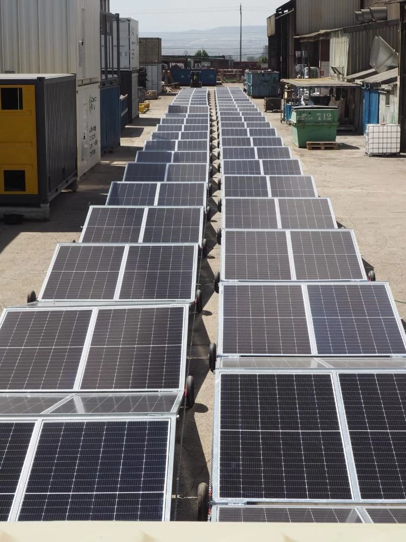 Monocrystalline solar panels stacked in warehouse.